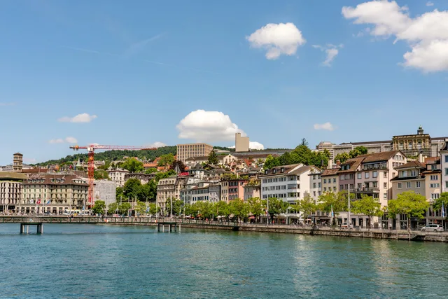 Beautiful waterfront scene in Zurich with historic architecture under a clear blue sky. Steuern für Schweizer Unternehmen: System, Fristen und Pflichten